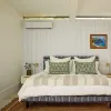 A bedroom with striped wallpaper on the back wall. There is a Quilt Indoor Unit on the back wall with a wallpapered front cover.
